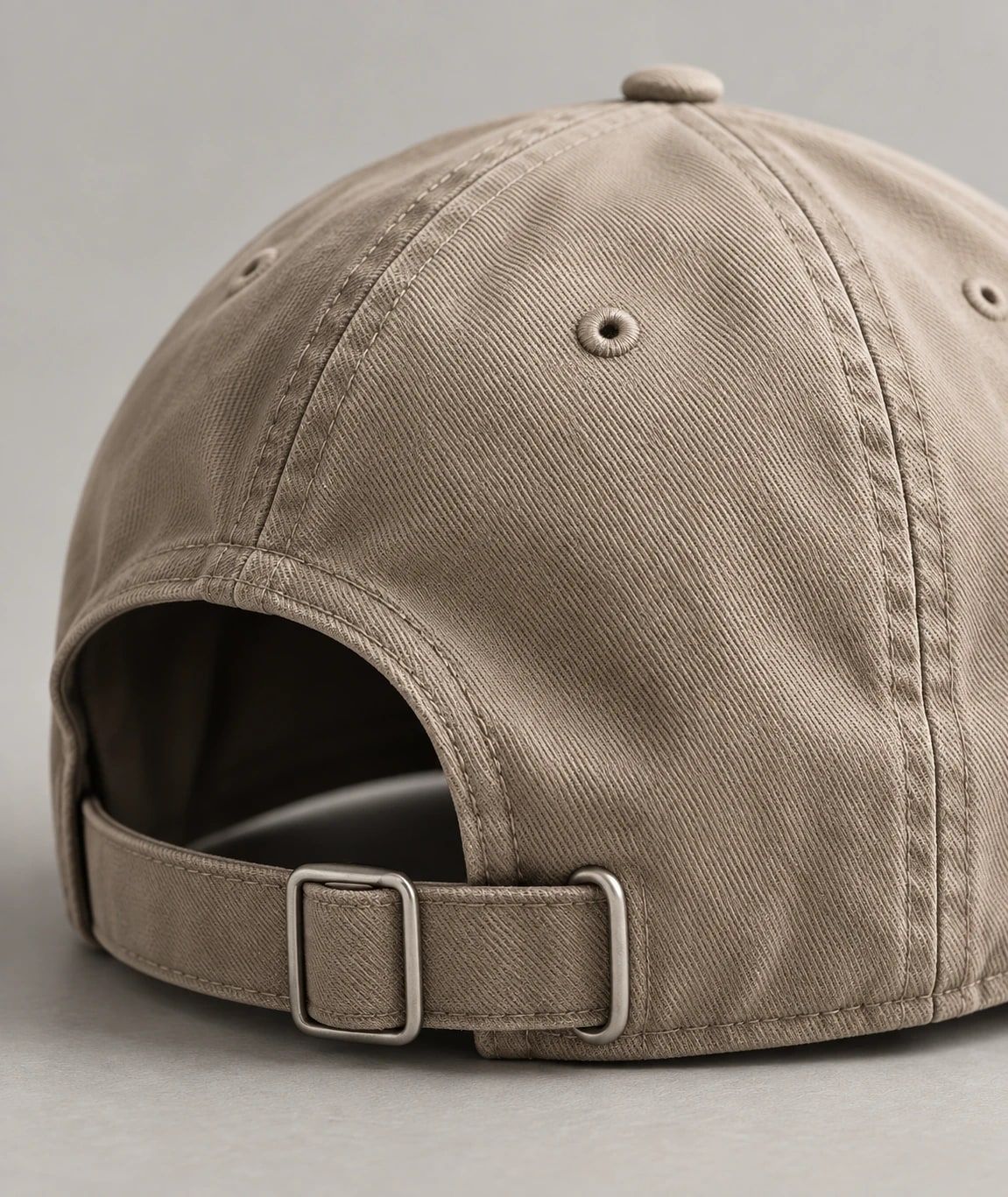 Back of a beige cotton twill cap with a metal buckle strap